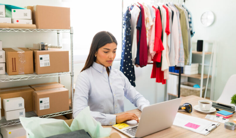 Business owner working on her sales report Focused female entrepreneur sitting at her office desk and updating the products and new fashion clothes on her online e-commerce